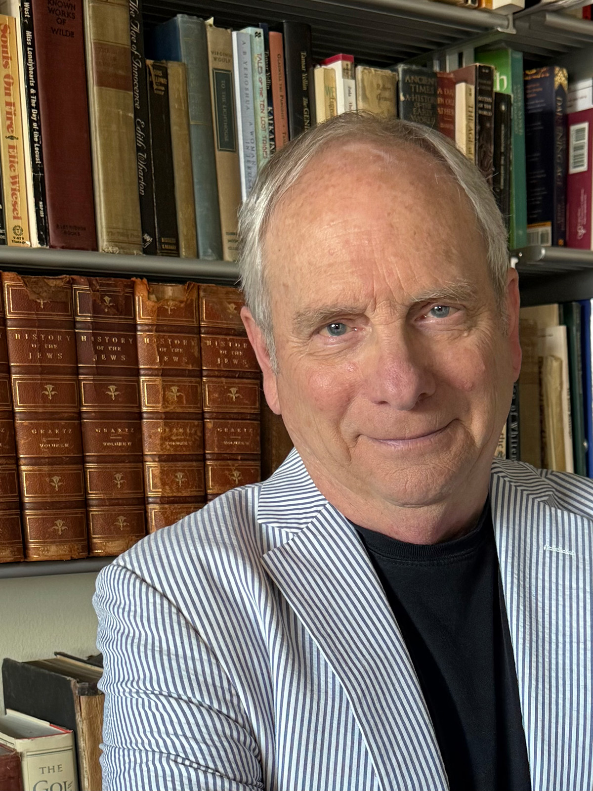 Portrait of author Michael Lavigne in front of his bookshelves